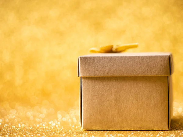 Braune Geschenkbox auf goldenem Glitzerhintergrund. — Stockfoto