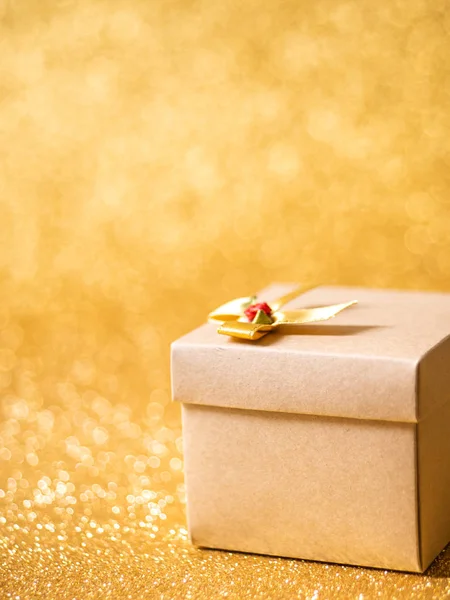 Braune Geschenkbox auf goldenem Glitzerhintergrund. — Stockfoto