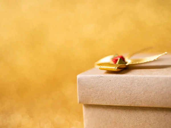 Brown gift box on gold glitter background. — Stock Photo, Image