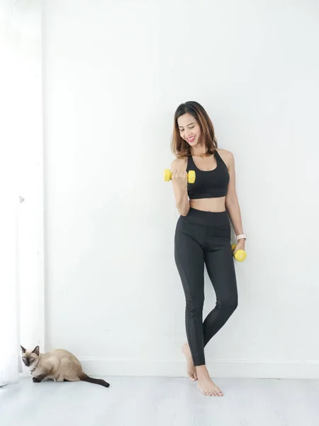 Asian woman exercise with dumbbell next to  her cat at home. — Stock Photo, Image