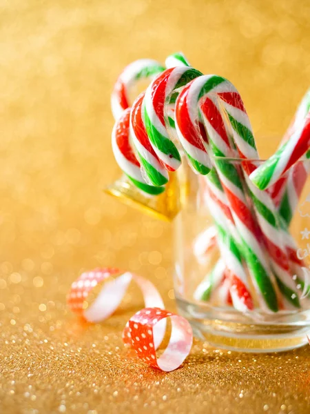 Bastoncini di caramelle di Natale su vetro con sfondo argento bokeh . — Foto Stock
