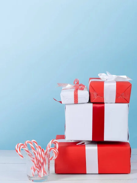 Rood-witte geschenkdozen en kerstsnoepgoed op houten ta — Stockfoto