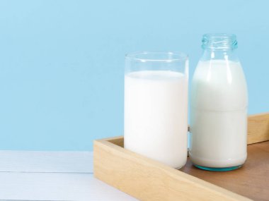 Süt şişesi mavi arka planlı masada..