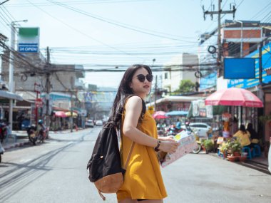 Sırt çantalı Asyalı kadın şehirde harita tutuyor, seyahat vizesi var.