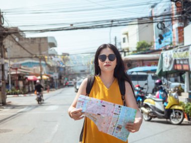 Sırt çantalı Asyalı kadın şehirde harita tutuyor, seyahat vizesi var.