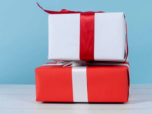 Caixas de presente vermelho e branco na mesa de madeira com parede azul . — Fotografia de Stock