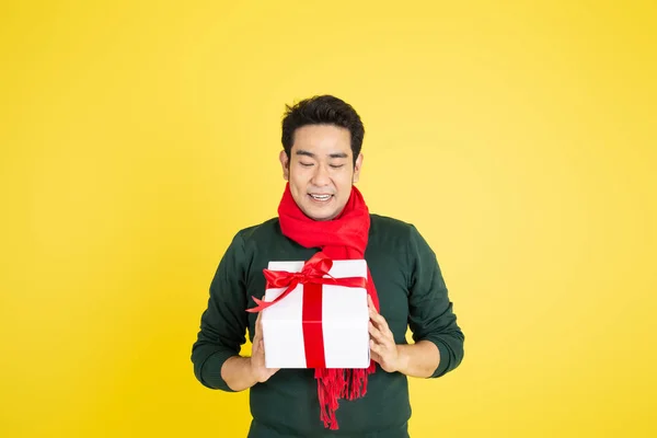 身穿绿色毛衣和红领巾的亚洲男子手持礼品盒o — 图库照片