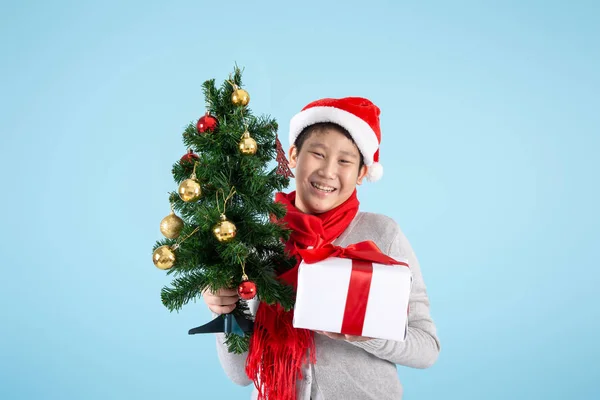 ハッピーアジアのpreteen男の子開催クリスマスツリーとギフトボックス上のb — ストック写真