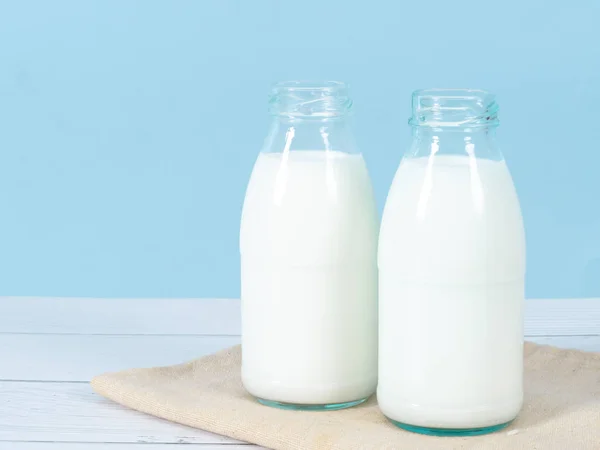 Láhev mléka na stole s modrým pozadím. — Stock fotografie