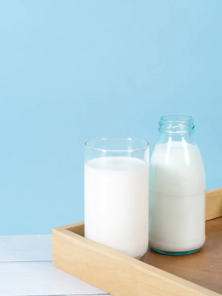 Láhev mléka na stole s modrým pozadím. — Stock fotografie