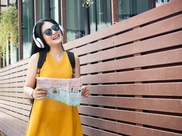 Asiatin mit Rucksack mit Kopfhörer und Landkarte in der Hand — Stockfoto