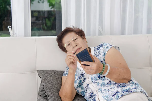 Kanepede akıllı telefon kullanan Asyalı son sınıf öğrencisi bir kadın. Yaşam tarzı kavramı. — Stok fotoğraf