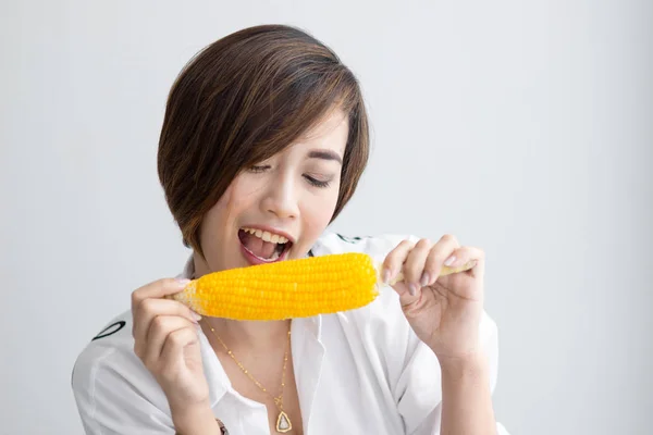 Asian girl eating yellow corn at home. — Stock Photo, Image