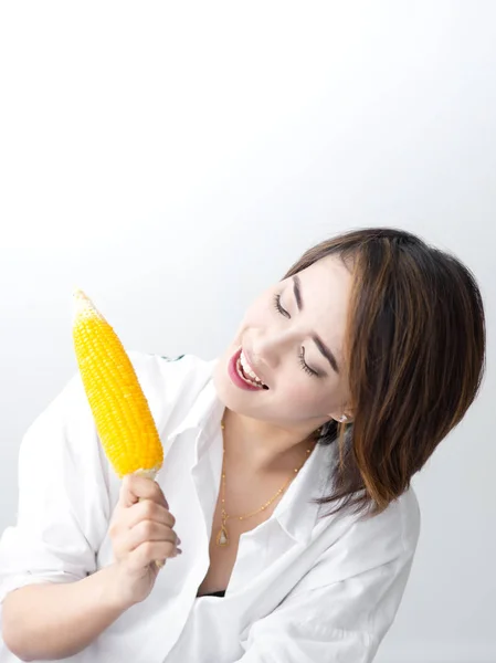 Asian girl eating yellow corn at home. — Stock Photo, Image