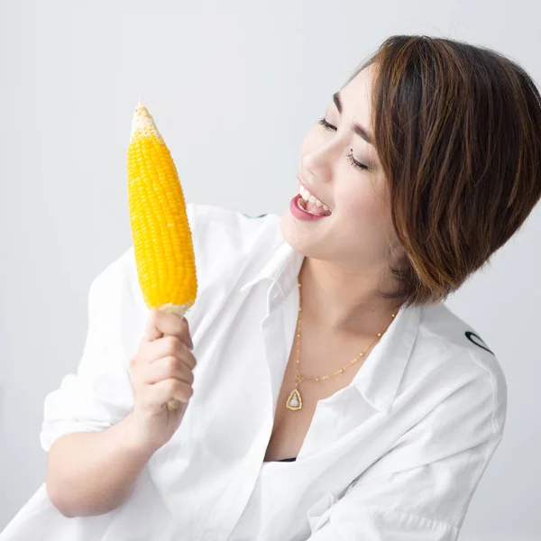 Asian girl eating yellow corn at home. — Stock Photo, Image