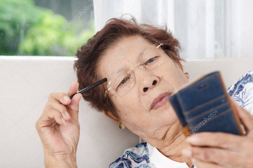 Asian senior woman using smartphone on sofa. Lifestyle concept.