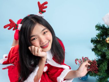 Noel Baba kostümü giymiş Asyalı genç kız yerde yatıyor.