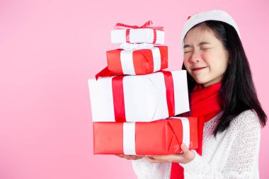 Mutlu Asyalı genç kız pembe arka planda hediye kutuları tutuyor.