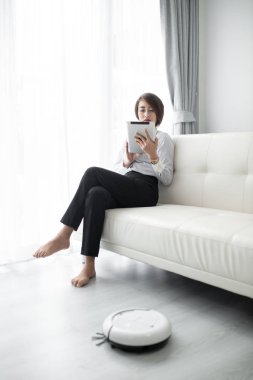 Akıllı iş kadını akıllı tablet ve temizlik robotu kullanıyor.