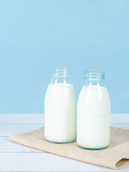 Botella de leche sobre la mesa con fondo azul . — Foto de Stock