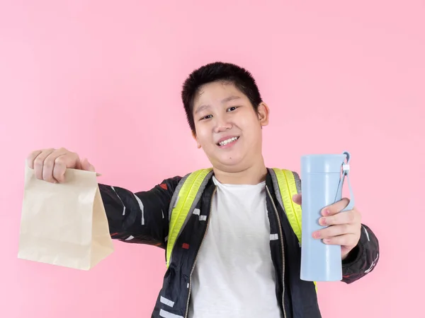 Asiático preadolescente chico mostrando bolsa de almuerzo y bebida botella, listo para s —  Fotos de Stock