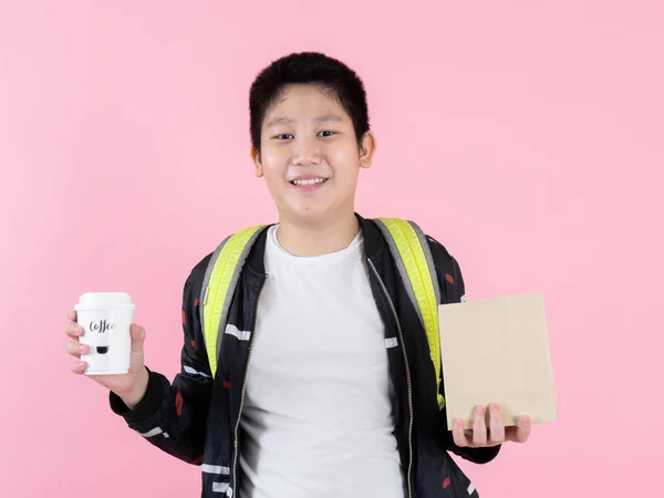 Feliz asiático preadolescente chico mostrando almuerzo bolsa y café takeaway en —  Fotos de Stock