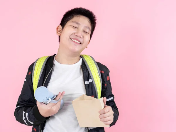 Asiático preadolescente chico mostrando bolsa de almuerzo y bebida botella, listo para s —  Fotos de Stock