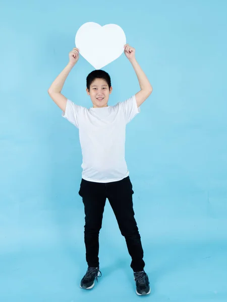 Asian preteen boy holding white heart shape speech bubble on blu — Stock Photo, Image