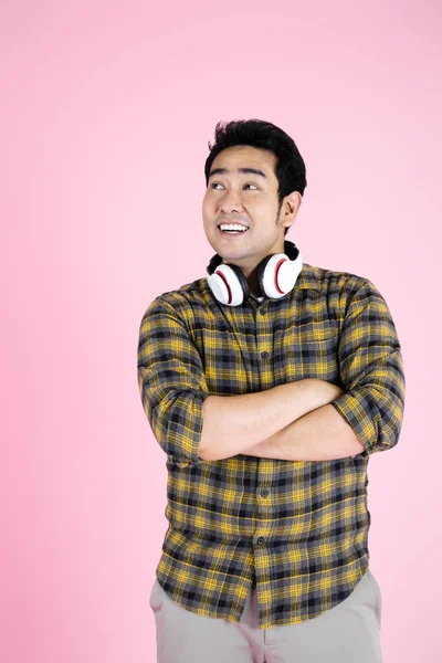 Feliz homem asiático vestindo camisa amarela e fone de ouvido no pano de fundo rosa — Fotografia de Stock