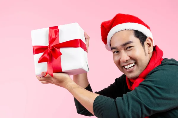 Happy Asian man wearing green sweater and Santa hat holding gift — Stock Photo, Image