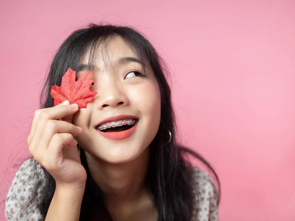 Asiatico adolescente ragazza con rosso acero su rosa sfondo. — Foto Stock