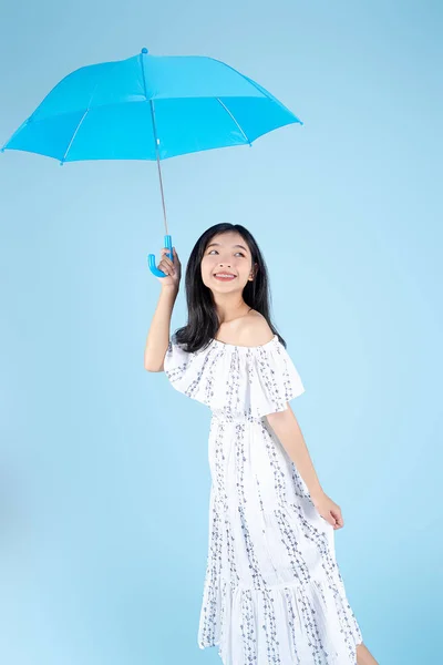 Asiatico donna indossare bianco abito lungo tenuta ombrello su blu ba — Foto Stock