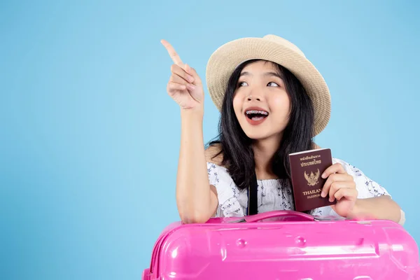 Feliz turista asiático que tiene pasaporte y equipaje apuntando hacia arriba. — Foto de Stock
