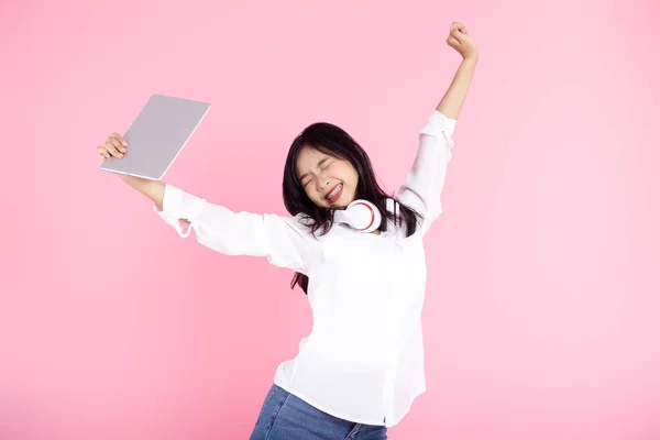 Asian teenager girl raising hands while using tablet on pink bac — Stock Photo, Image