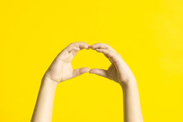 Kid's hands with sign language on yellow background. — Stock Photo, Image