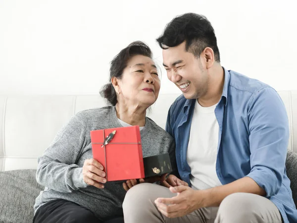 Happy Asian man giving gift box to his mother for Mother\'s Day c