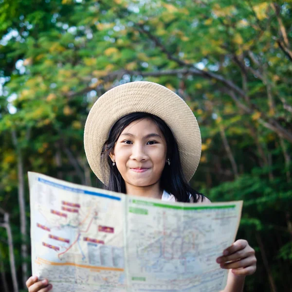 具有树木背景、生活方式概念的年轻女孩阅读地图. — 图库照片