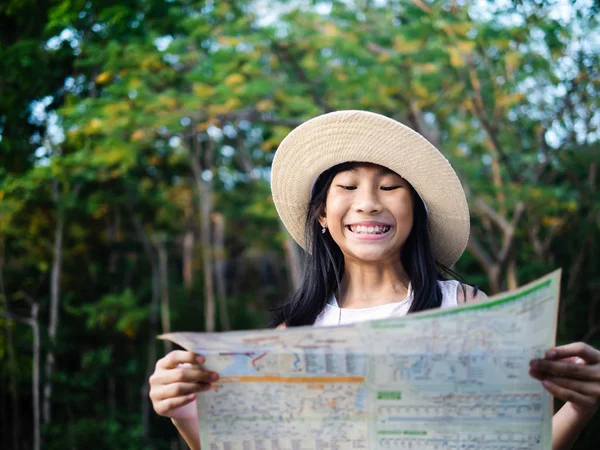 Young girl reading map with tree background, lifestyle concept. — Stock Photo, Image