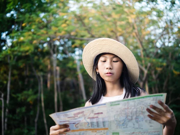 Young girl reading map with tree background, lifestyle concept. — Stock Photo, Image