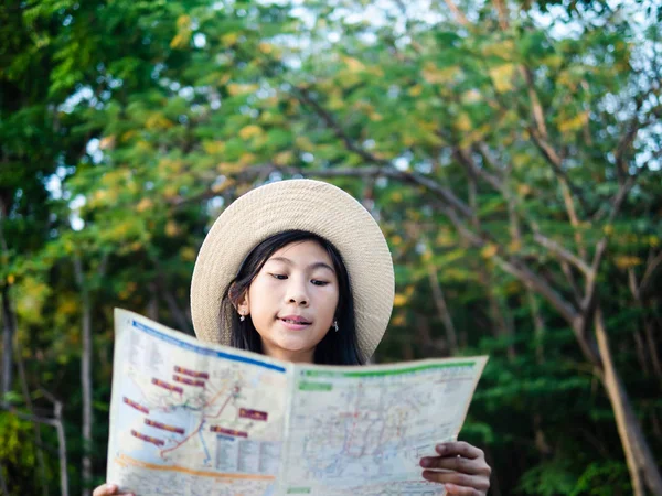 Young girl reading map with tree background, lifestyle concept. — Stock Photo, Image