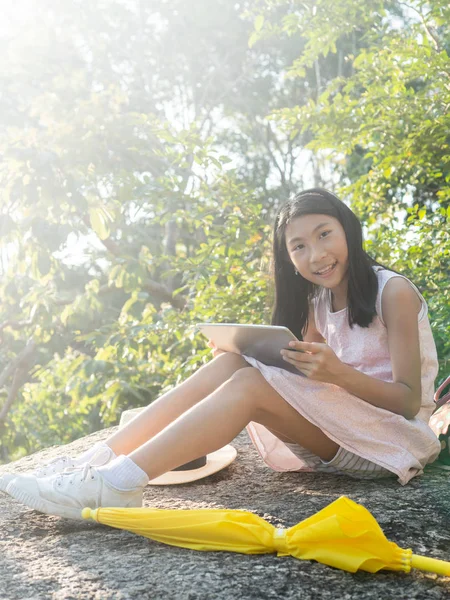 Asiatische Mädchen mit Tablette mit Sonnenlicht in der Natur, Lebensstil conce — Stockfoto