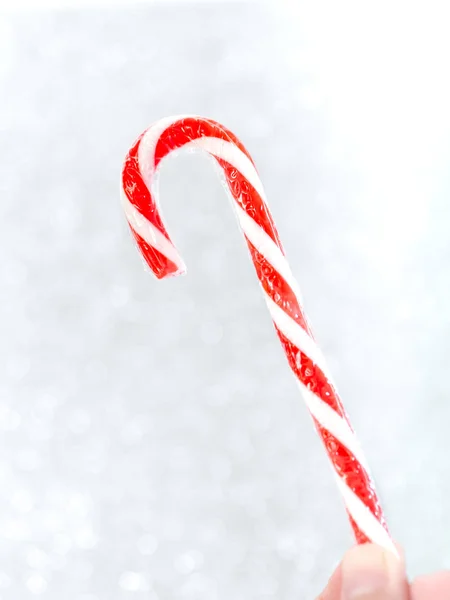 Hand gospodarstwa Christmas candy stick z bokeh tła. — Zdjęcie stockowe