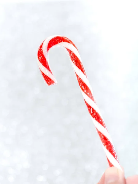 Mão segurando Natal doce vara com fundo bokeh. — Fotografia de Stock