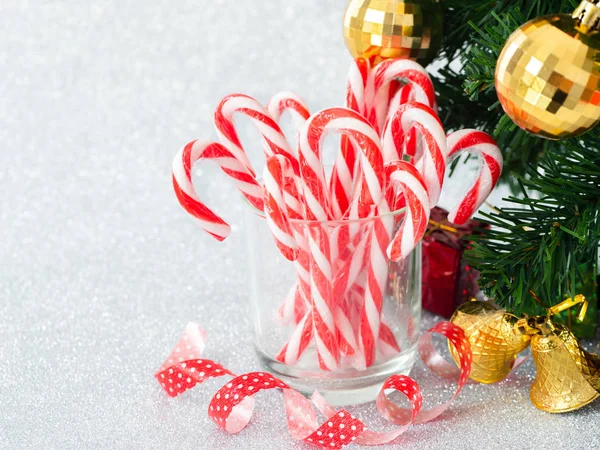 Christmas candy sticks on glass with silver bokeh background. — Stock Photo, Image