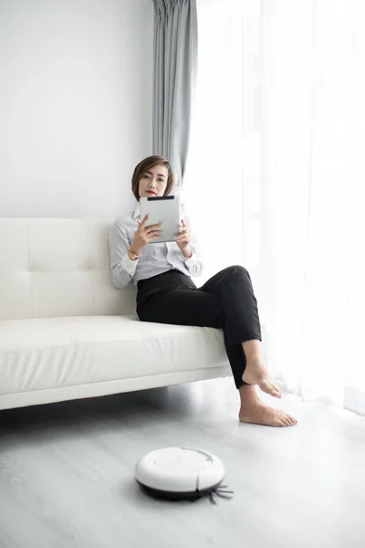 Inteligentna bizneswoman za pomocą inteligentnego tabletu i robota czyszczącego, życie — Zdjęcie stockowe