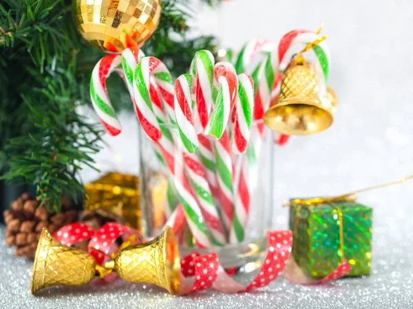 Christmas candy sticks on glass with silver bokeh background. — Stock Photo, Image