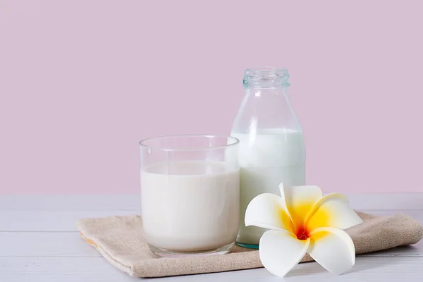 Lait en verre et bouteille à fond rose. — Photo