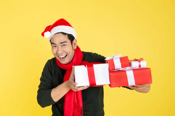 Happy Asian man wearing green sweater and Santa hat holding gift Stock Photo