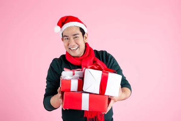 Happy Asian man wearing green sweater and Santa hat holding gift Royalty Free Stock Photos