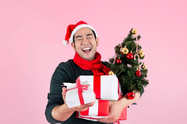 Happy Asian man wearing green sweater and Santa hat holding gift Stock Picture